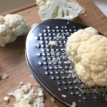 Pieces of raw cauliflower and a grater