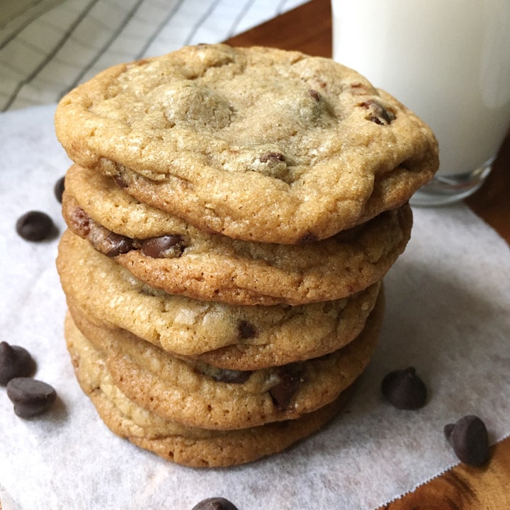 Close-up of a stack of chocolate chip cookies next to a glass of milk