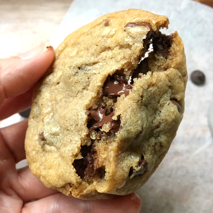 Close-up of a chocolate chip cookie being broken in half, melted chocolate chips in the cookie
