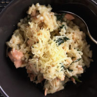 A bowl of salmon spinach risotto and a spoon