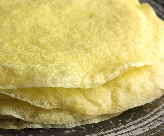 A stack of yellow Flourless Crepe Tortillas on a plate