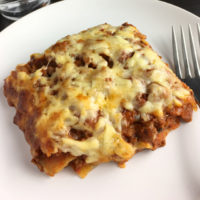 A piece of lasagna on a plate with a fork