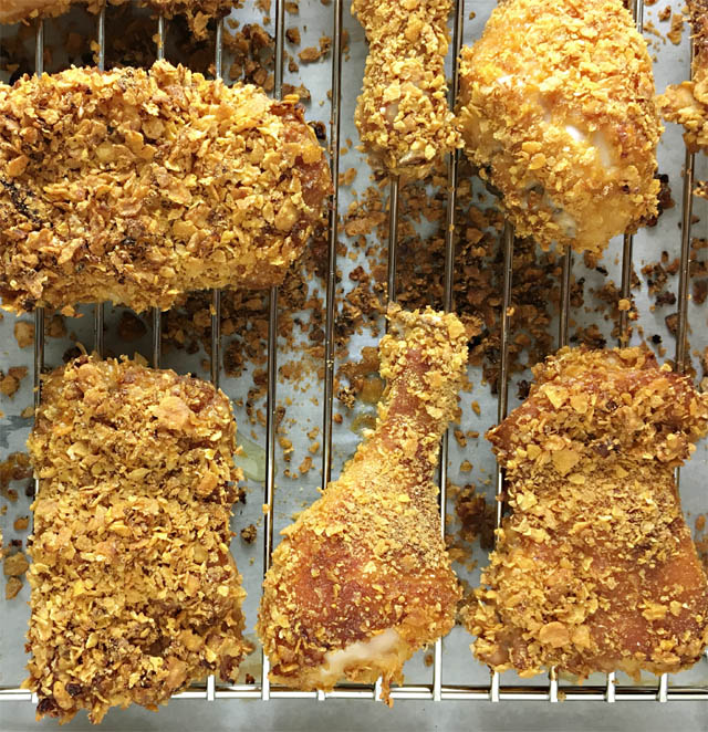Cornflakes chicken on a metal rack on a baking sheet