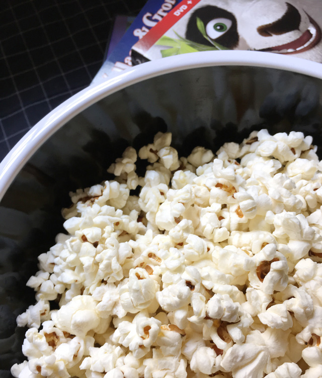 A black and white bowl of Easy Perfect Stovetop Popcorn with DVD cases in the background