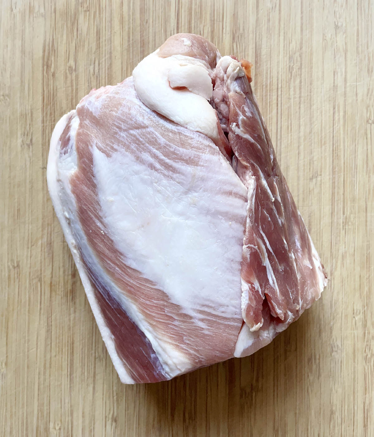An uncooked pork roast on a wooden cutting board.