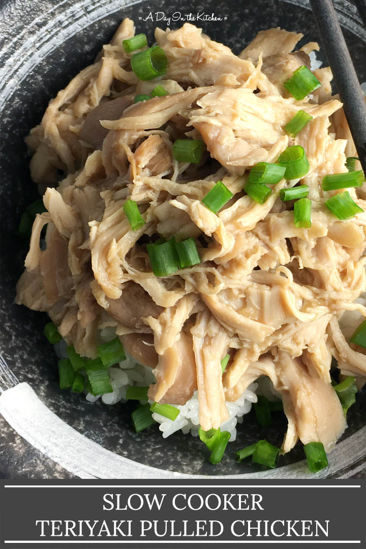 Close-up of a round dark bowl containing white rice, pulled chicken, and chopped green onions