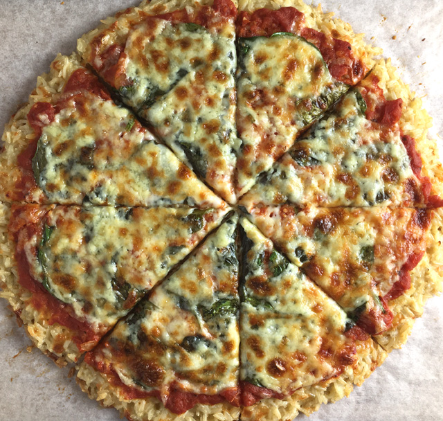 A whole Rice Crust Pizza made of rice, tomato sauce, spinach, and cheese