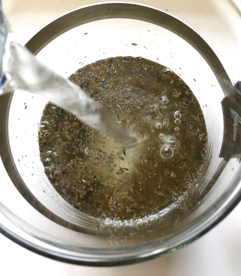 Water pouring into a carafe containing loose tea leaves to make Cold Brewed Tea