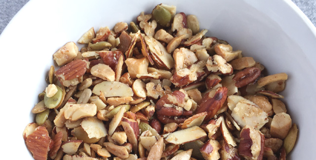 Close-up of a white bowl of Easy Grain Free Nutty Granola with almonds, pecans, cashews, sesame seeds, and pumpkin seeds