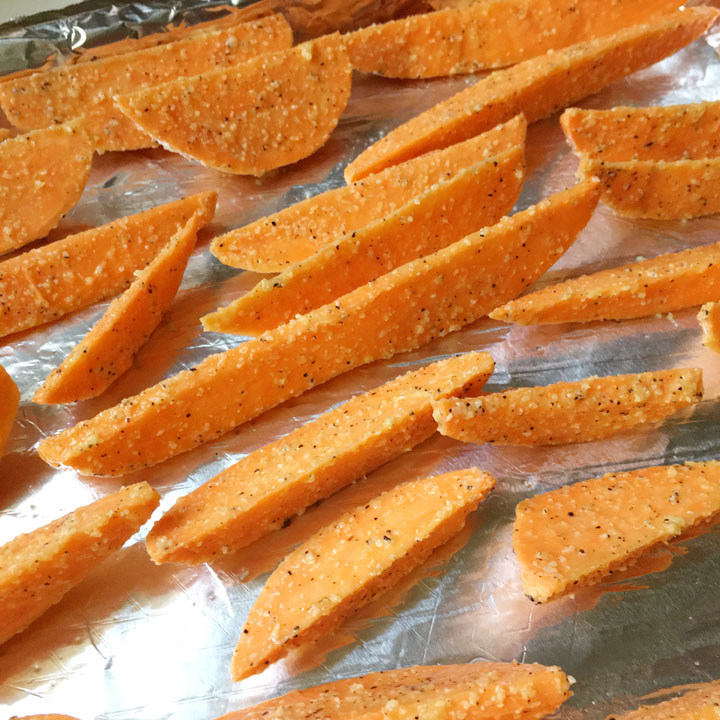 Orange sweet potato wedges in a single layer on foil lined baking sheet
