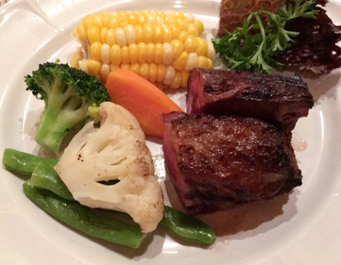 A white plate with steak, corn, cauliflower, broccoli, carrots, and green beans at La Pampa