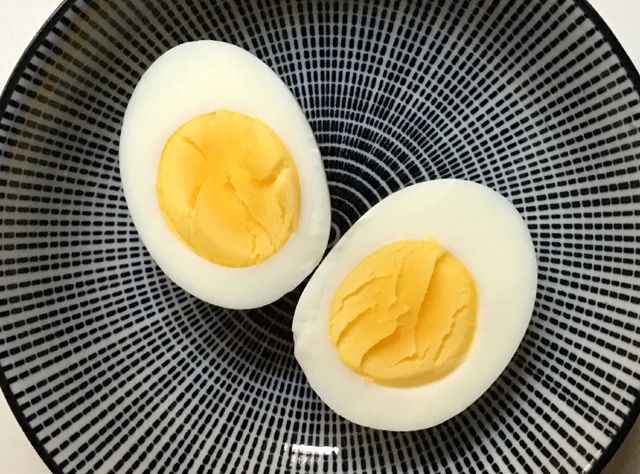 Hard cooked egg cut in half on a round plate. Cook Eggs In A Rice Cooker