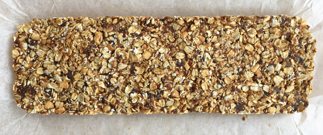 An uncut slab of Simple Nutty Granola Bars with rolled oats, nuts, and chocolate chips