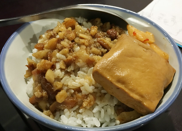 A bowl of braised ground pork over rice and a square of tofu - eat in Taipei