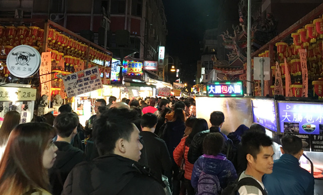 Walking the crowd-filled lane with food stalls at the Shilin Night Market in Taipei