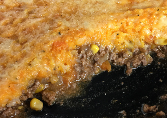 A round black pan of Sweet Potato Cauliflower Shepherd's Pie, consisting of a layer of mashed sweet potatoes and cauliflower over a layer of ground beef