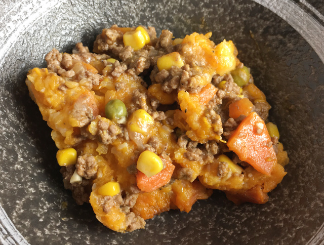 A bowl of Sweet Potato Cauliflower Shepherd's Pie containing sweet potatoes, cauliflower, ground beef, peas, carrots, and corn