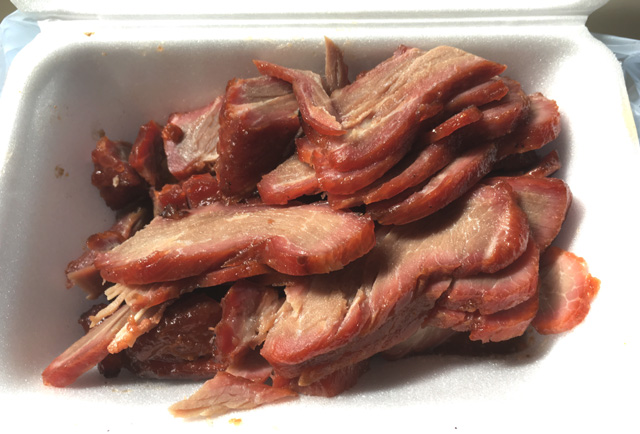A white styrofoam container with sliced barbecued pork for BBQ pork chow mein
