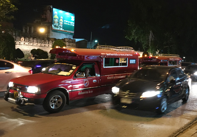 A street view showing red trucks in traffic in Chiang Mai