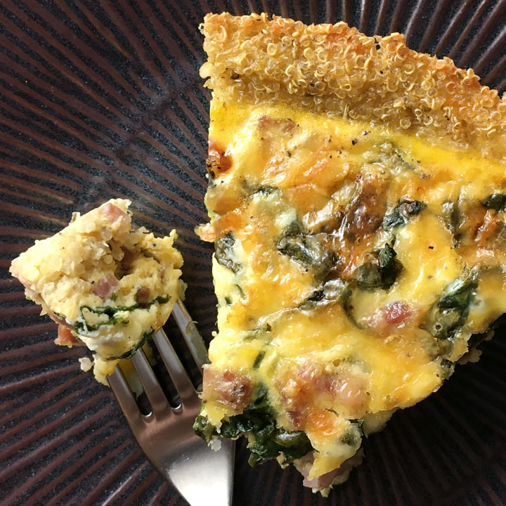 A brown round plate containing a triangular piece of quiche and a fork