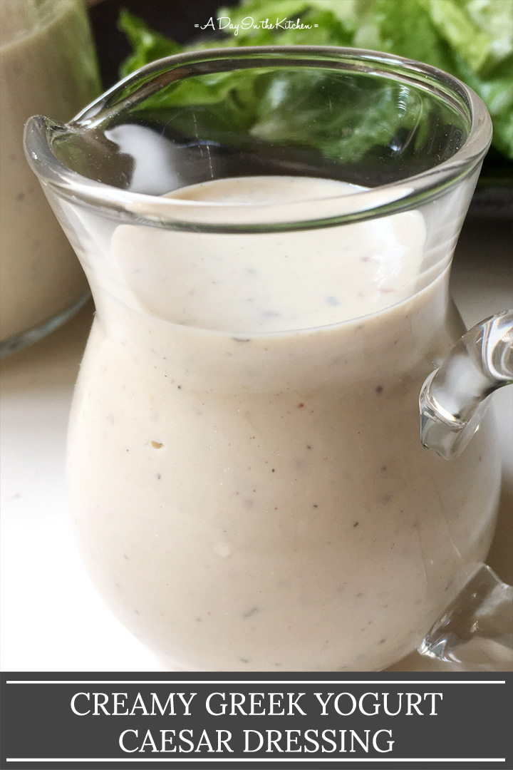 A small glass pitcher containing white dressing, the words creamy Greek yogurt Caesar dressing on the bottom