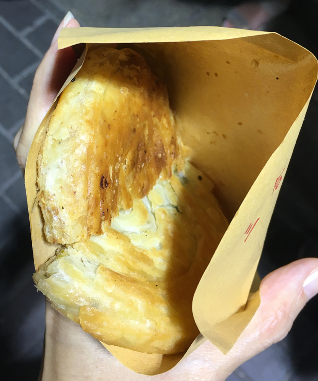 Two Sichuan pancake halves in a paper bag on a Hong Kong foodie tour