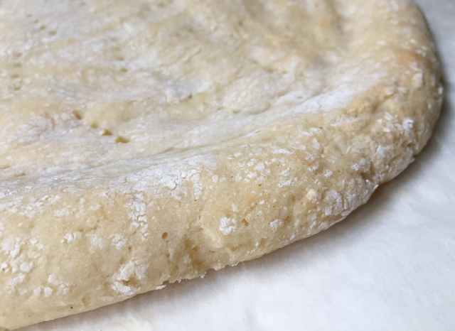 Close-up of a baked gluten-free pizza crust on parchment paper