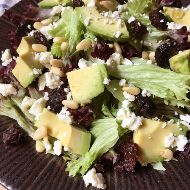 Close-up of avocado feta salad with dried cherries, pine nuts, and leaf lettuce