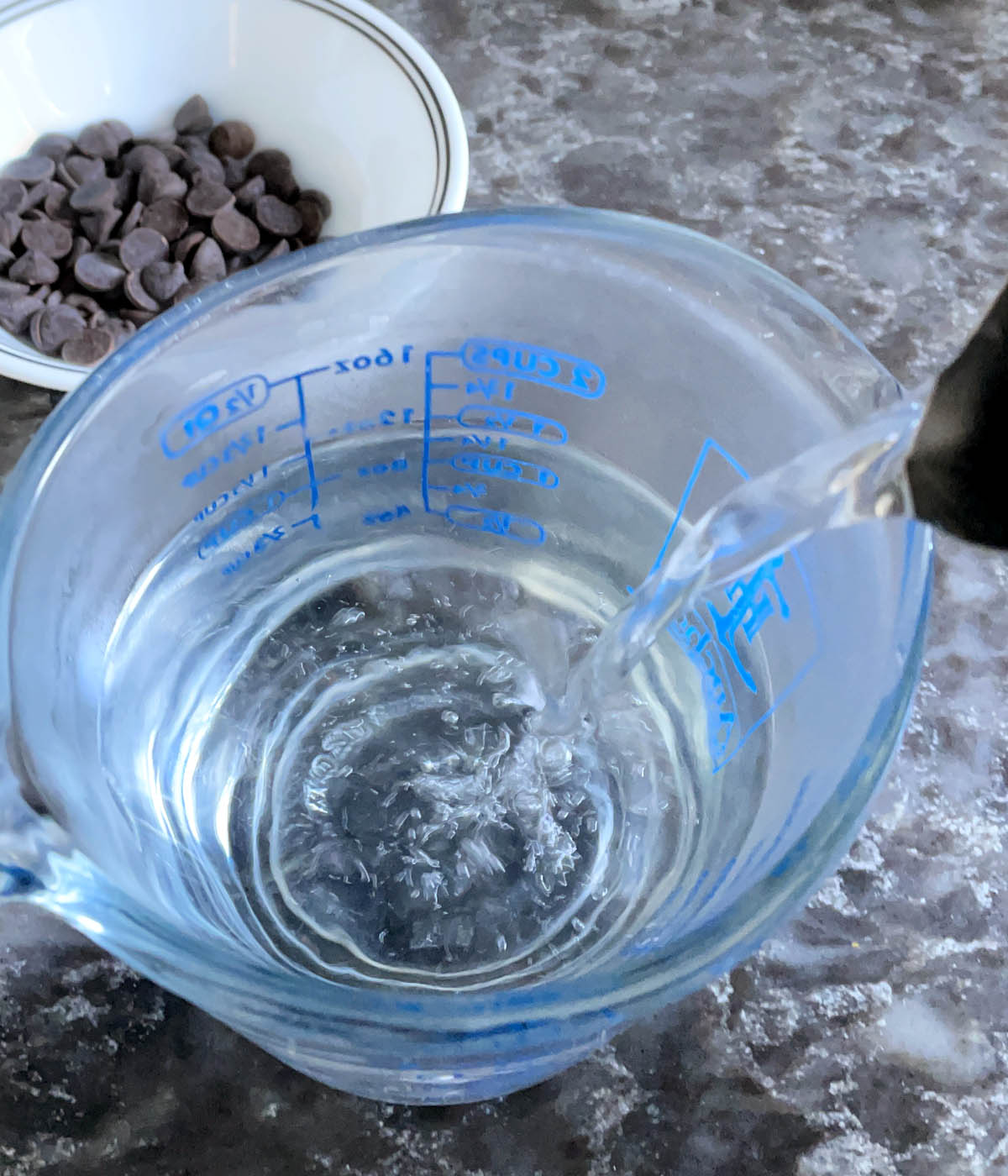 Hot water being poured from a kettle into a glass measuring cup.