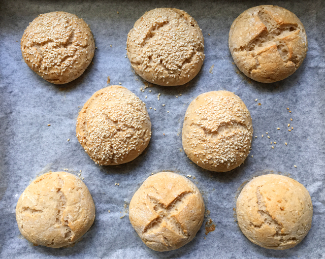 Eight gluten-free buns on a parchment paper lined baking sheet 