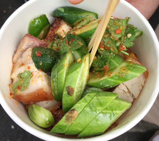 A round white bowl containing chunks of pork belly and cucumber slices