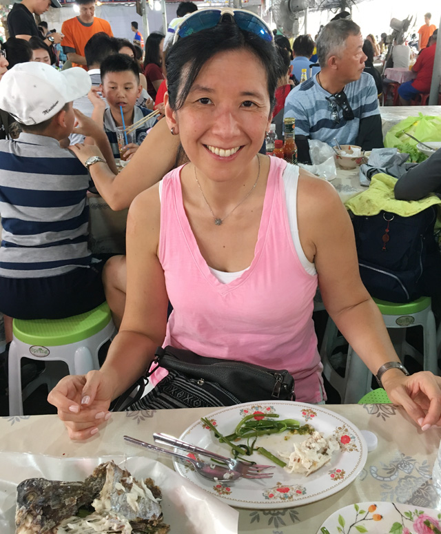 A woman in a pink shirt having a meal in a crowded outdoor dining area