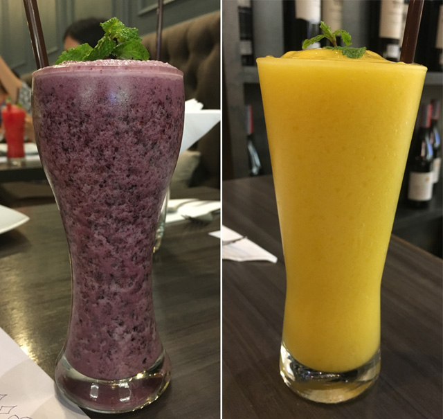 Two tall glasses, one containing a blue drink, another containing an orange drink