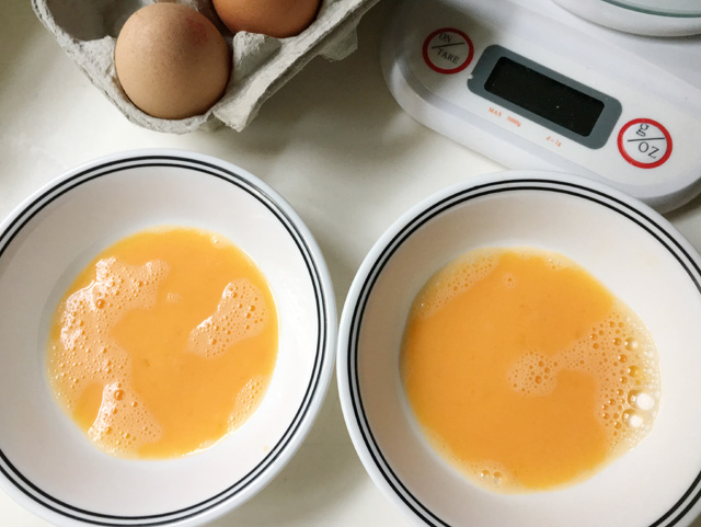 Two white bowls containing equal portions of raw egg for how to halve an egg