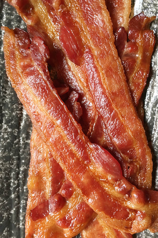 Close-up of several slices of bacon for a crowd on a grey plate