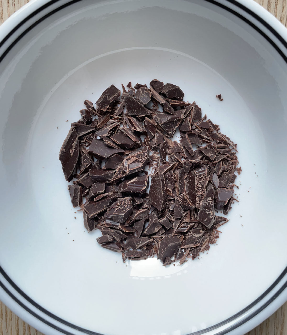 A white round bowl containing finely chopped chocolate.
