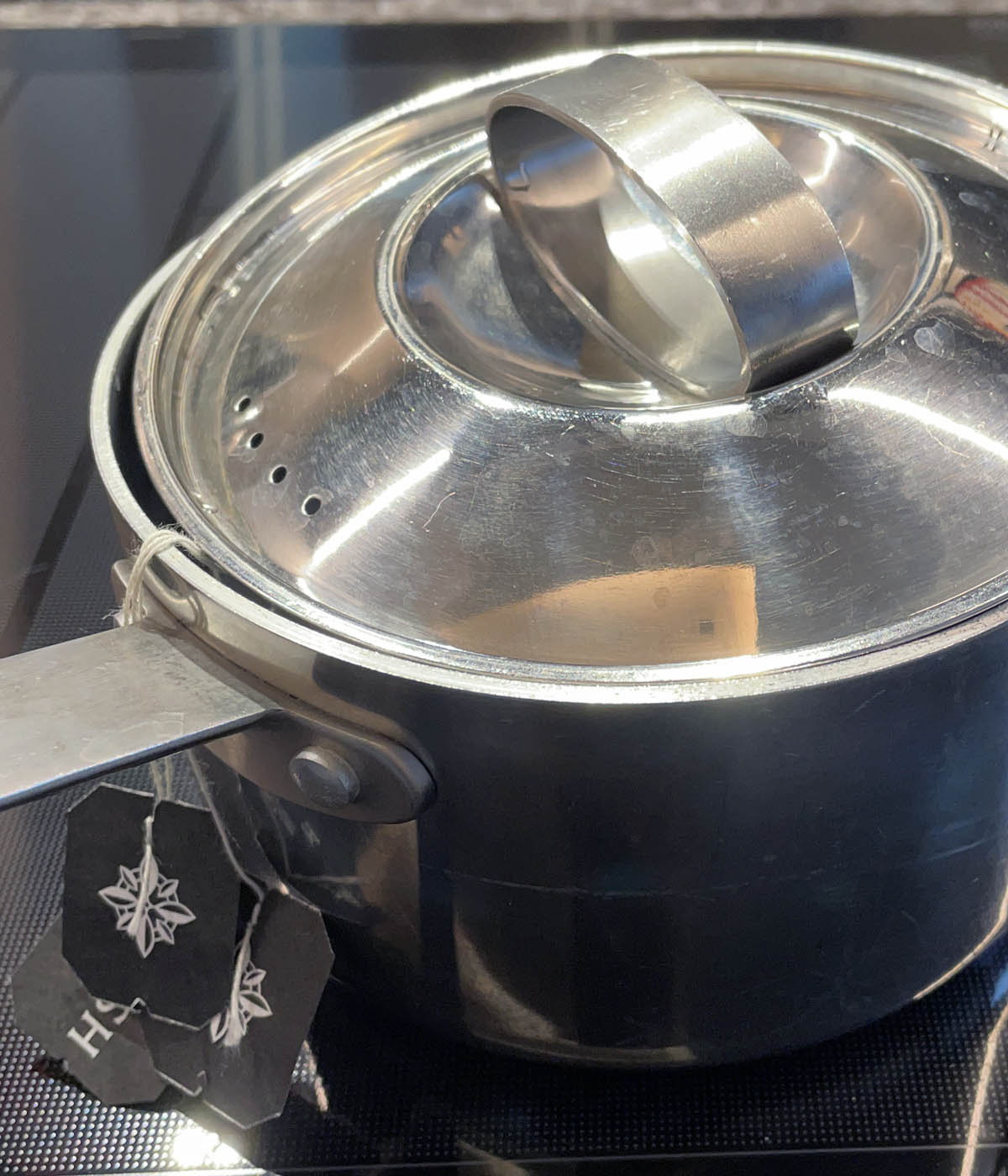 A metal pot with the lid on and tea bag strings hanging over the edge.