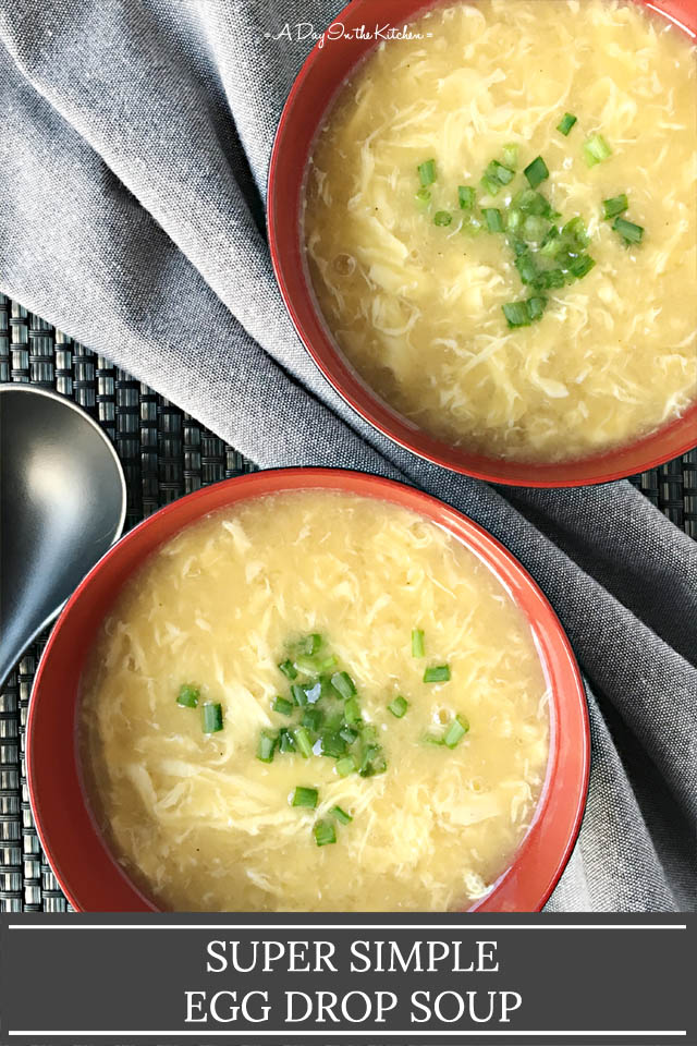 Two red bowls of egg drop soup topped with chopped green onion