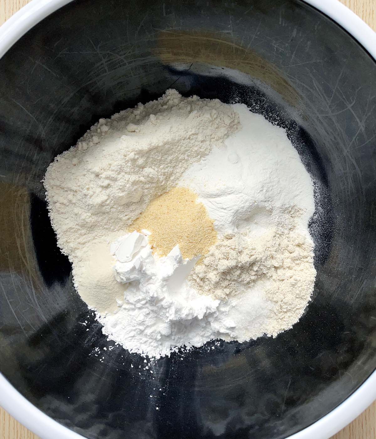A black bowl containing different dry flour ingredients.