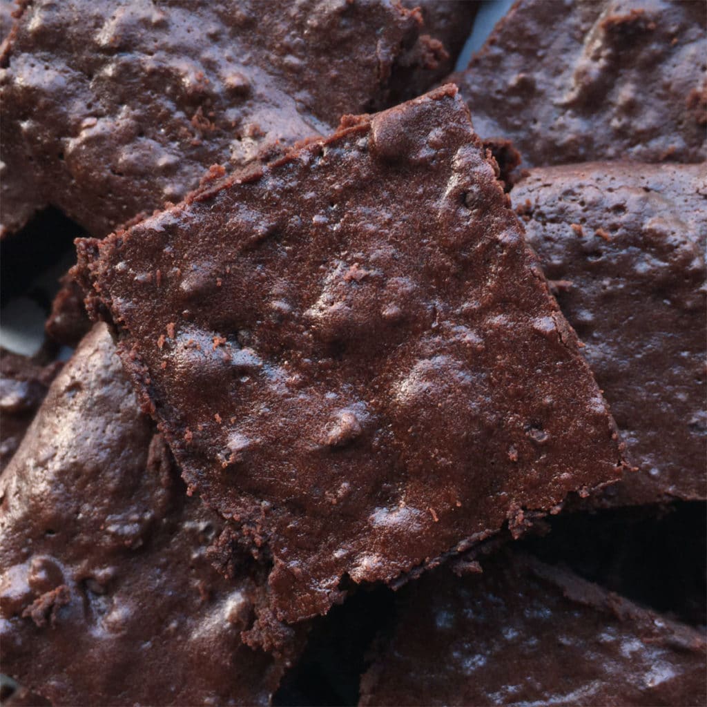 Close-up of a chocolate brownie square on top of a pile of brownies