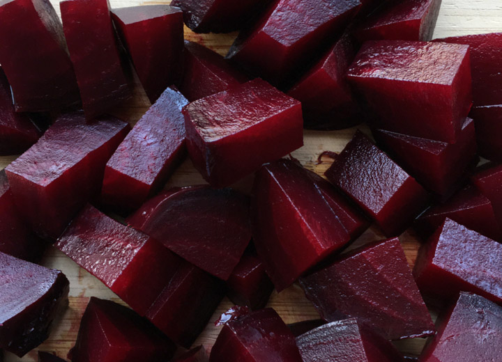 Chunks of red beets on a wooden cutting board