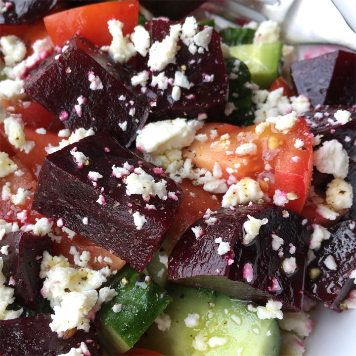 A salad of beet chunks, cucumbers, tomatoes, and white feta cheese crumbles