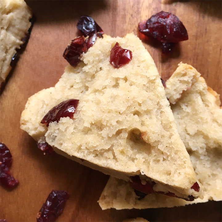 Close-up of the inside of a cranberry scone, resting on a brown wood surface