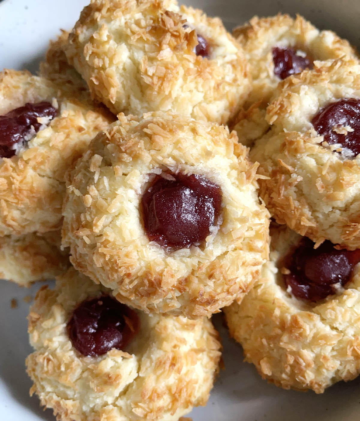 Closeup of jam filled cookies coated with browned coconut flakes.