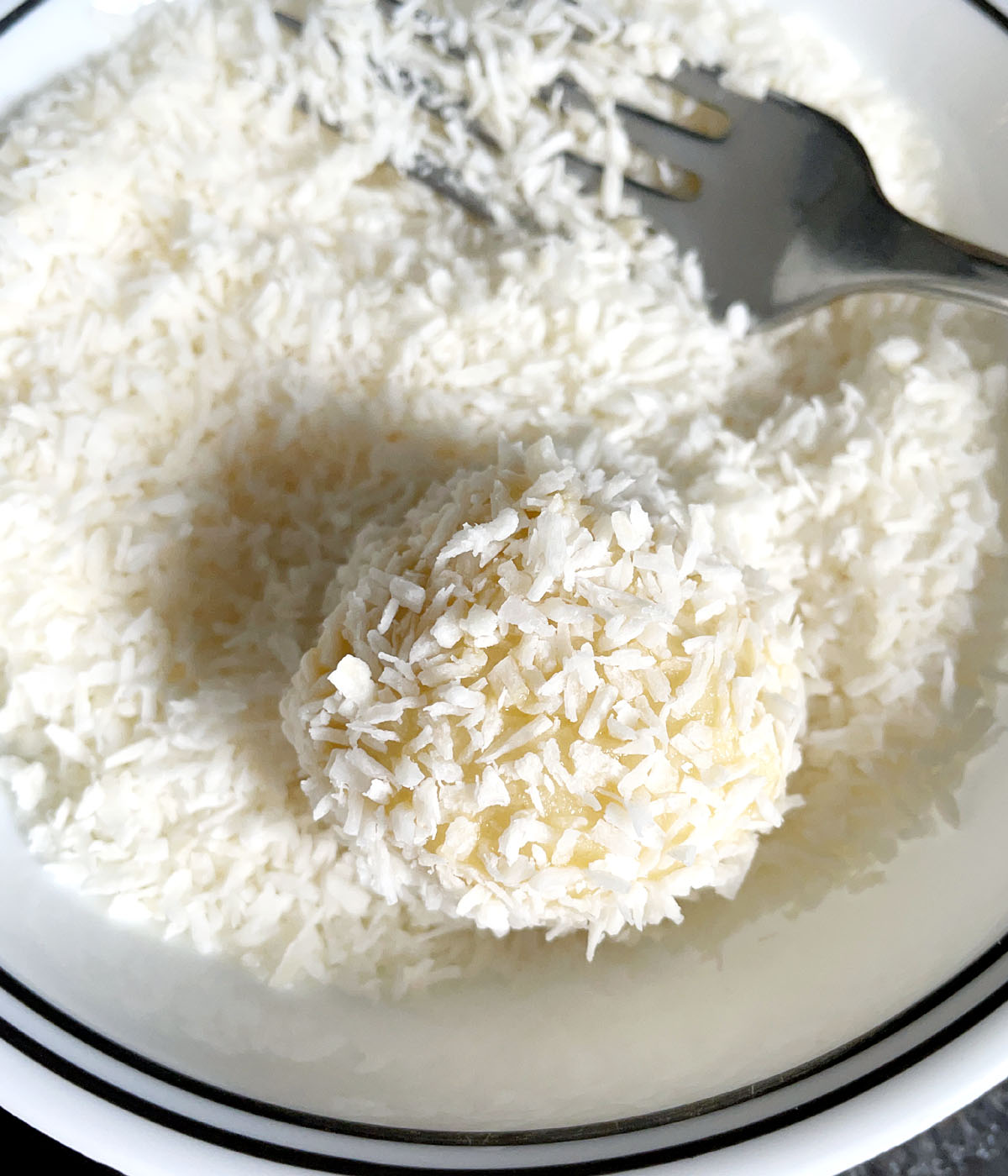 A ball of dough coated in a white coconut flakes.