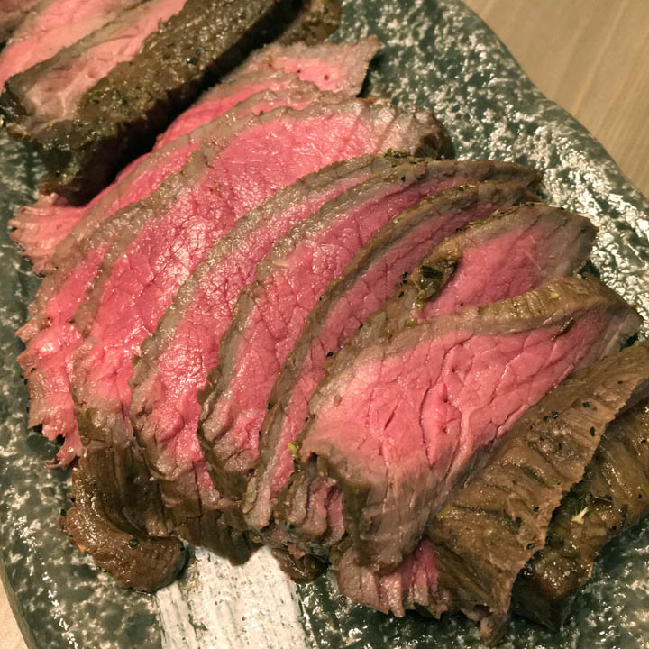 Thin brown and pink slices of steak on a stone dish