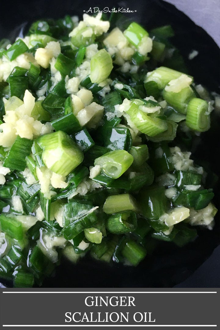 A black bowl containing chopped green scallions and minced ginger in oil, the words ginger scallion oil on the bottom