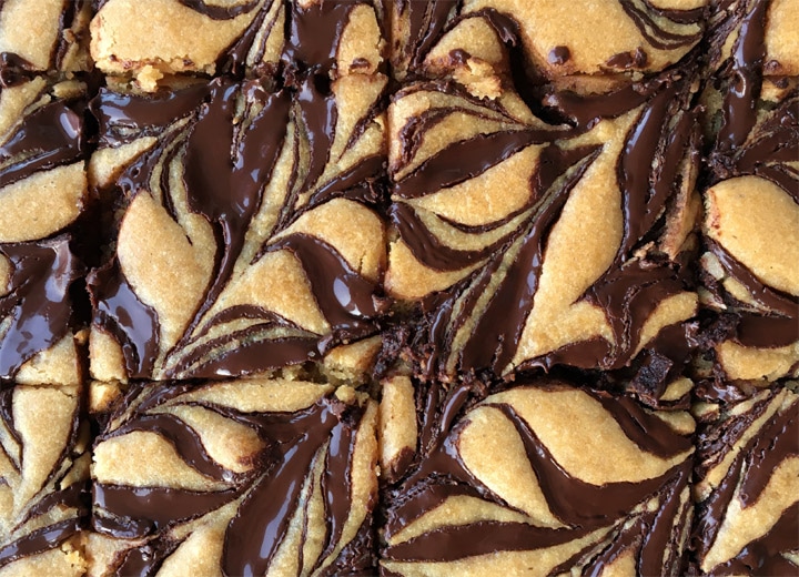 Close-up of yellow baked squares with dark brown chocolate swirls