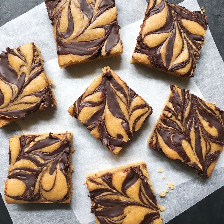 Seven squares of chocolate swirled baked squares on white parchment paper