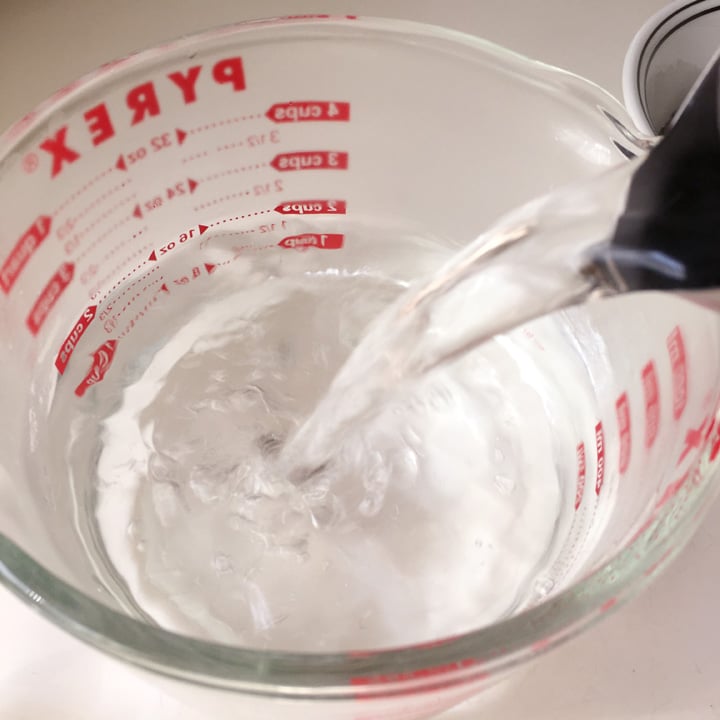 Water being poured into a glass measuring cup from a kettle